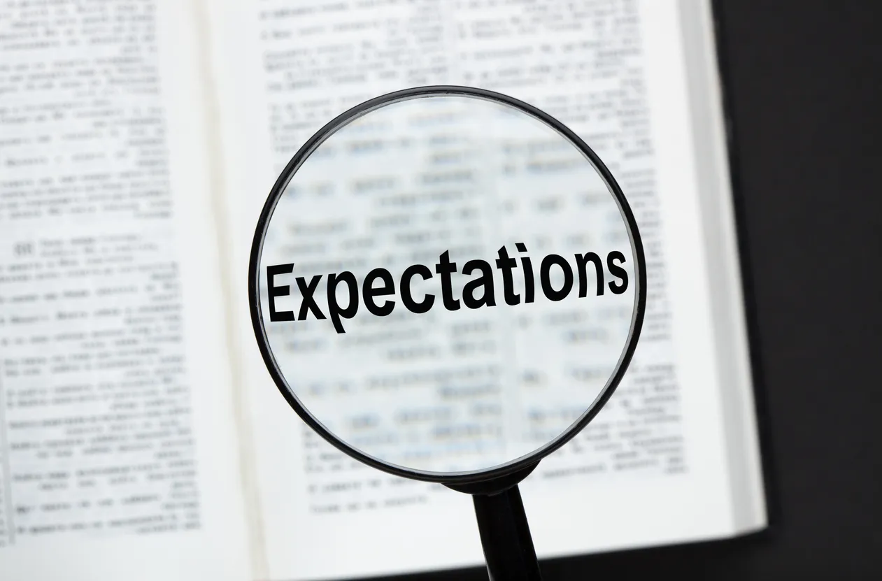 A magnifying glass highlighting the word expectation in a dictionary