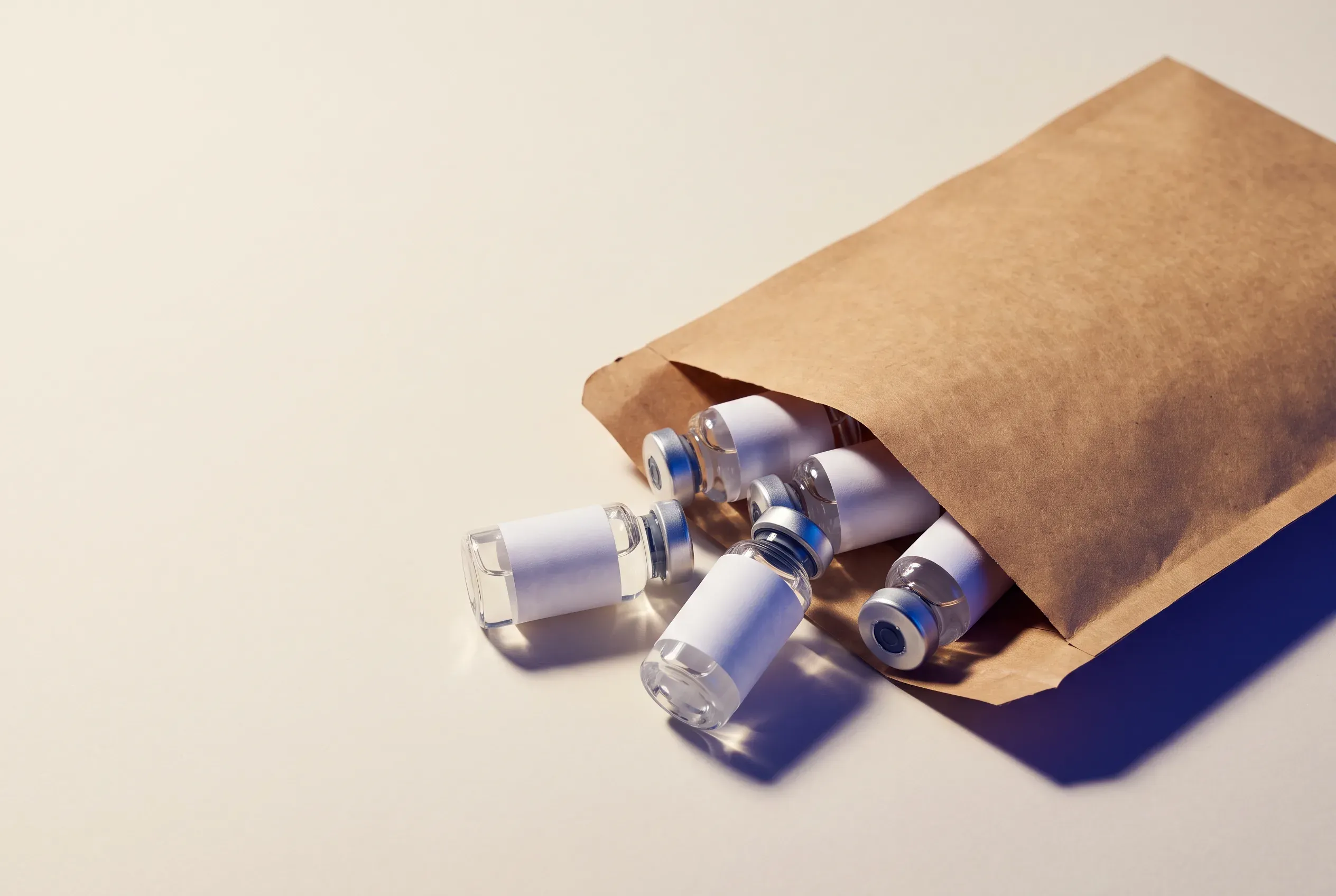 Unlabeled injection vials spilling from a plain shipping envelope, illustrating the risk of buying unregulated ‘research peptide’ retatrutide online.