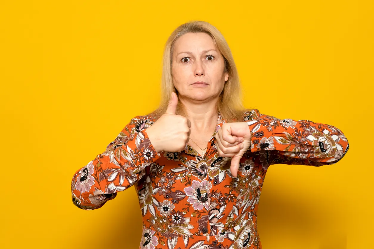 Une femme avec un pouce pointé vers le haut et l’autre vers le bas.