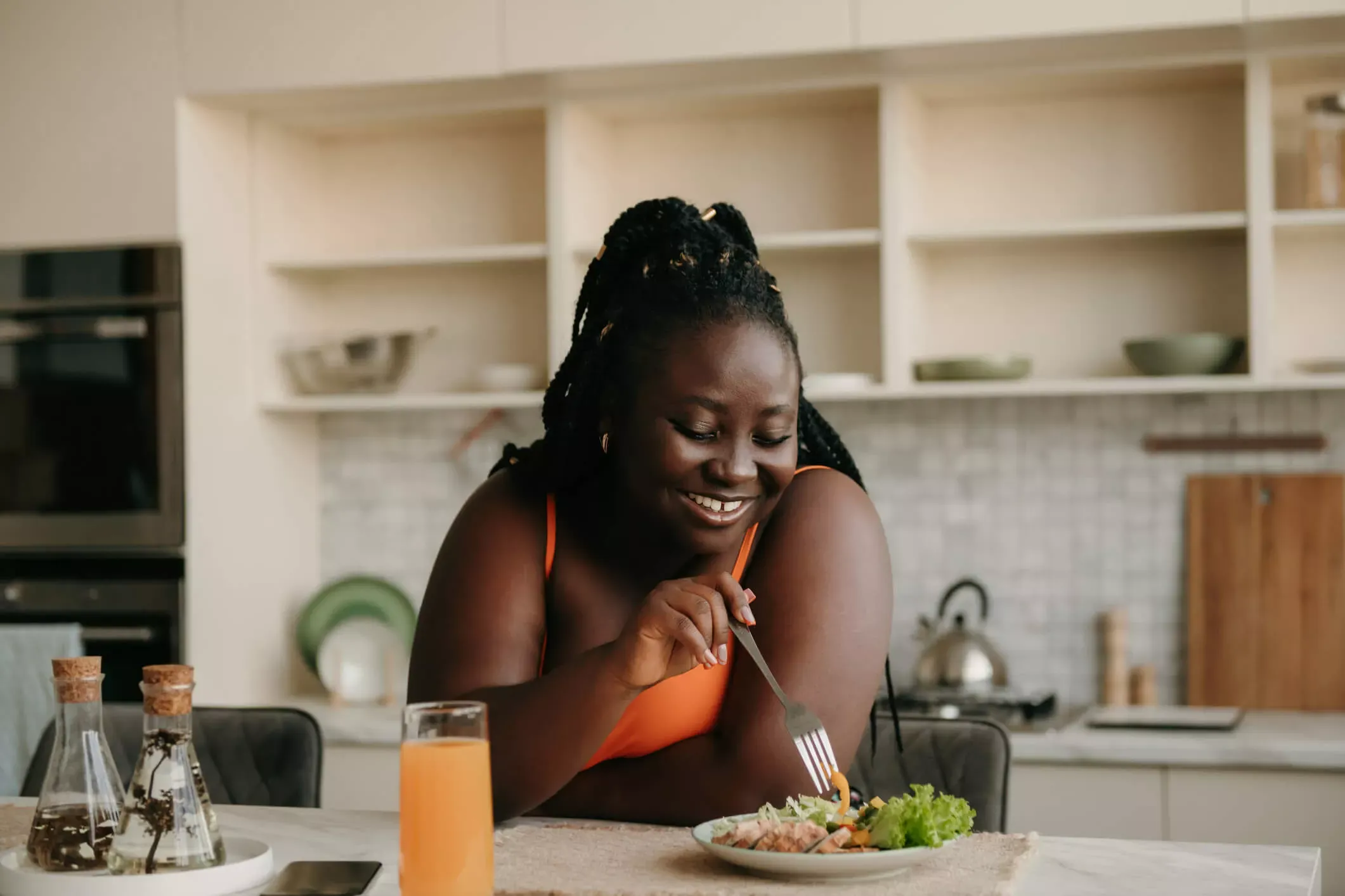 Jeune femme joyeuse mangeant à un comptoir de cuisine