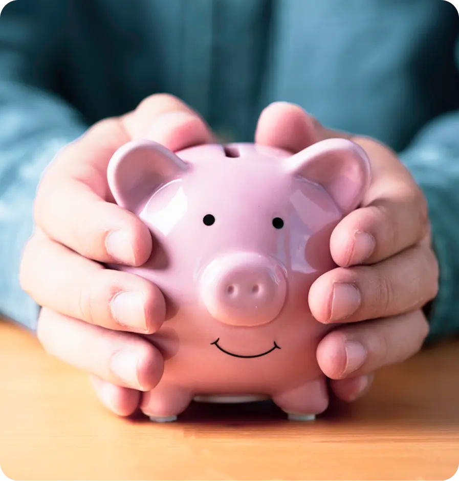 Close-up of a man's hands clasped around a pink piggy bank resting on a table—symbolizing saving and financial mindfulness.