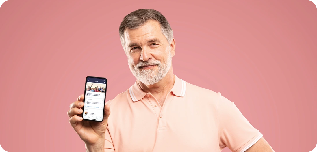Homme barbu d'âge moyen tenant le téléphone intelligent vers la caméra, pointant vers l'appareil affichant l'écran d'accueil de l'application Constant Health.